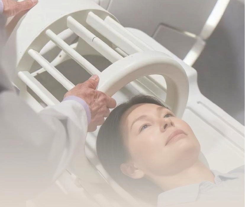 Patient on an MRI bed with the Innovia dual-tuned multi-nuclear head coil being placed by a clinician
